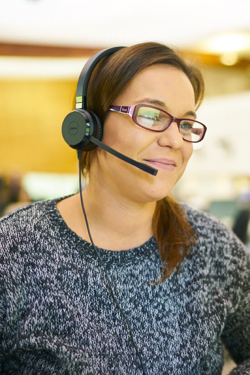 A customer service rep smiling while wearing a headset.