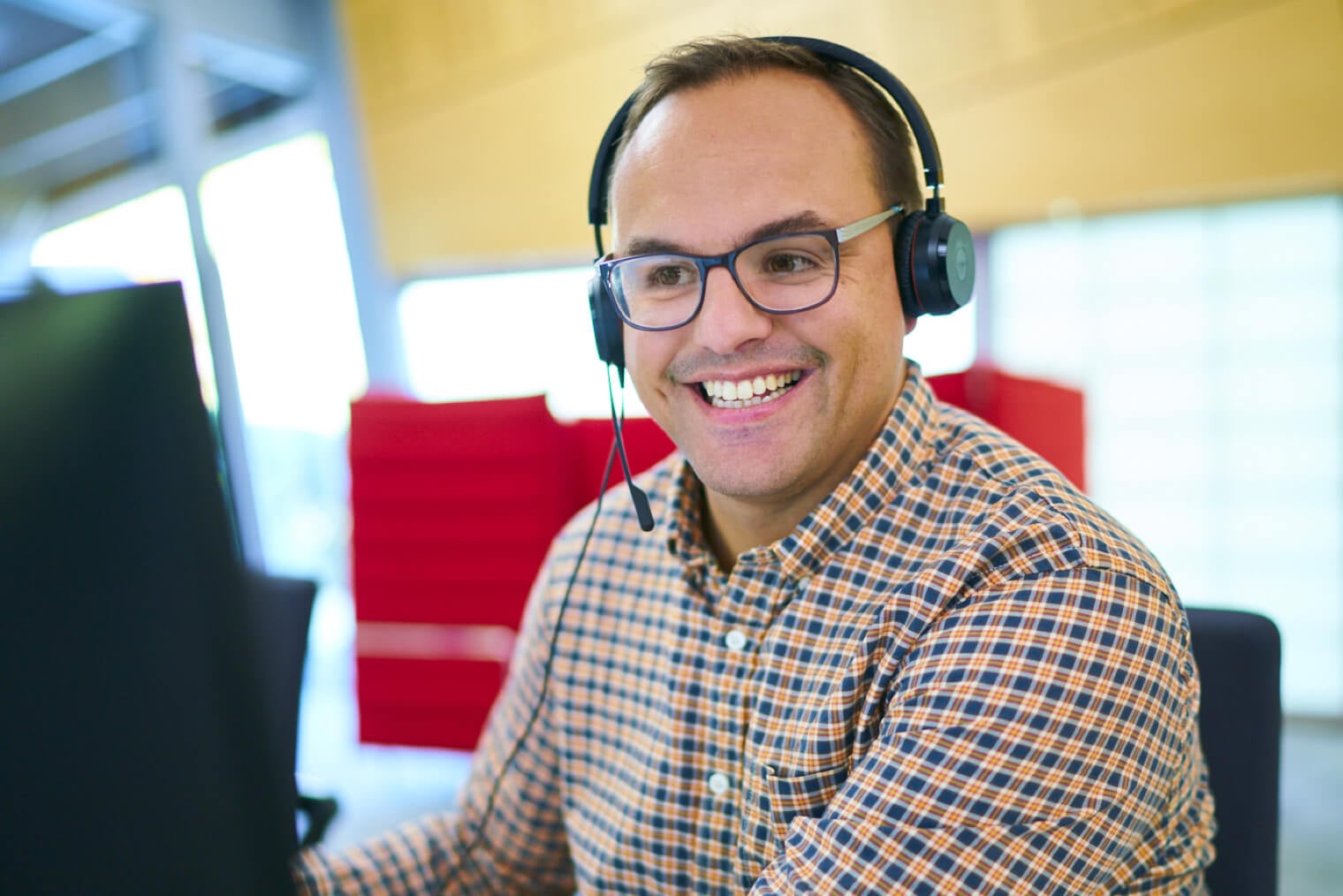 A customer service rep looking very happy while wearing a headset.